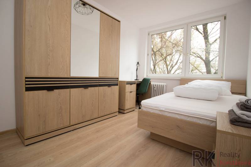 Hálószoba egy háromszobás lakásban ággyal, szekrénnyel és fa dekorációjú padlóval.