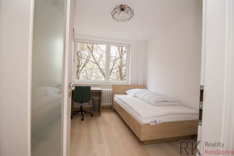 Egyágyas hálószoba ággyal, íróasztallal és fa dekorációjú padlóval egy háromszobás lakásban.