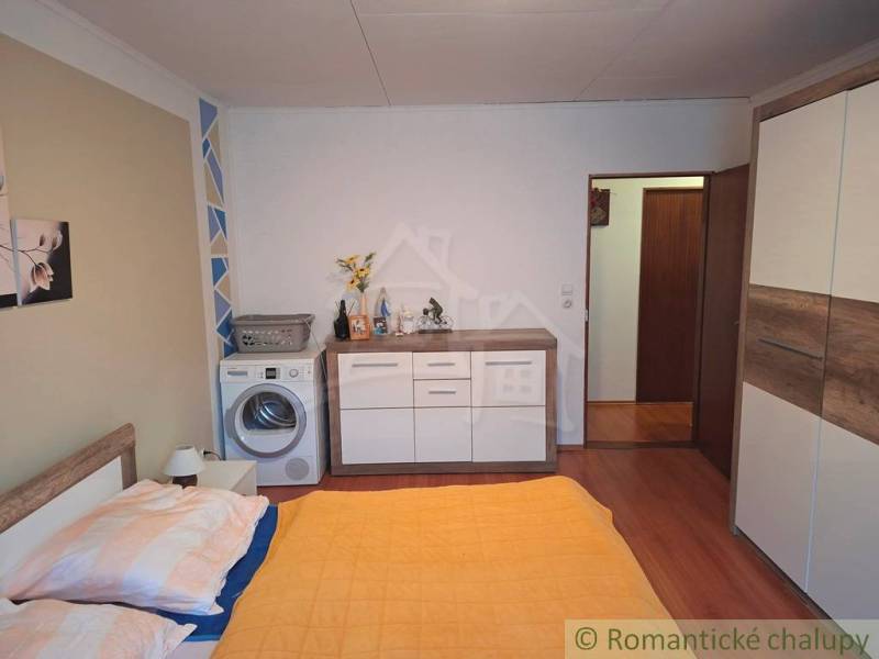 Hálószoba családi házban mosógéppel, szekrénnyel és fa padlóburkolattal.