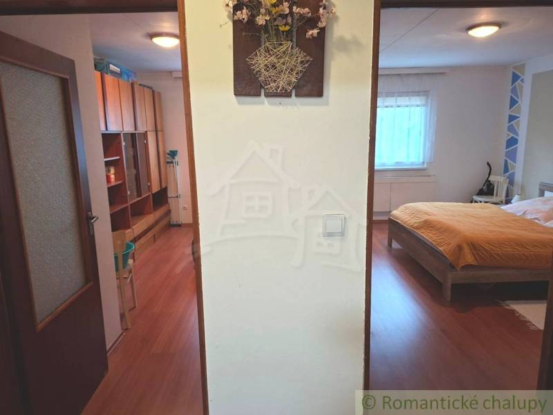 Családi ház belső tere fa dekorációjú padlóval, hálószoba és tárolóhely.