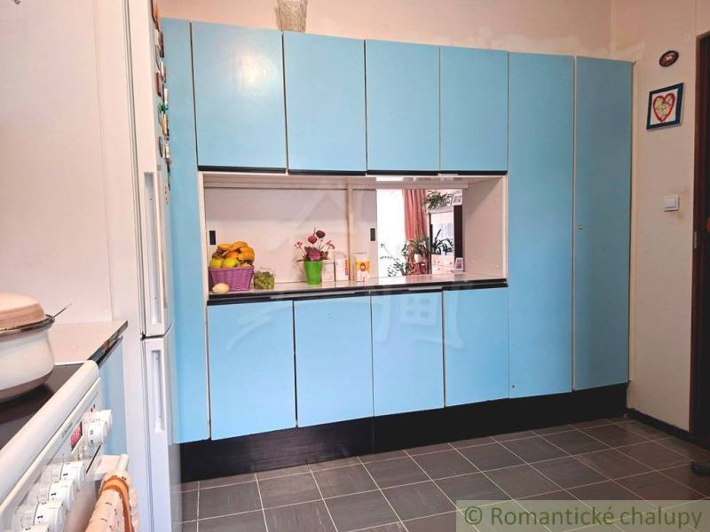 Konyha egy családi házban kék szekrényekkel és fehér készülékekkel.