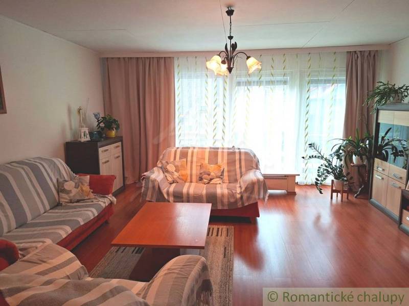 Nappali egy családi házban, fa dekorációjú padlóval, világítással és kanapékkal.