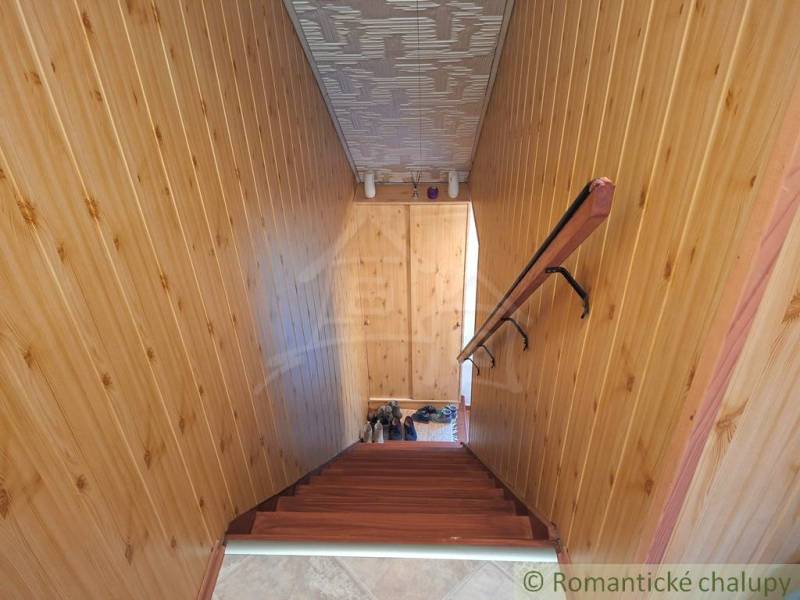 Családi ház belső tere fa burkolatú falakkal és fa dekorációjú lépcsővel.