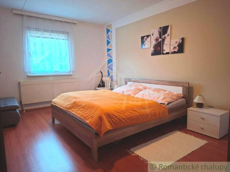 Hálószoba családi házban ággyal, dekorációval és fa dekoros padlóval.