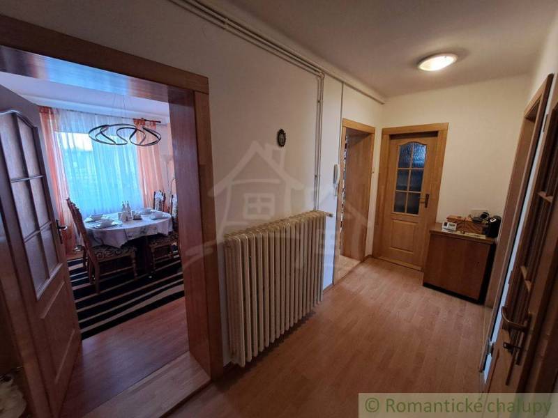 Folyosó fa mintázatú padlóval egy családi házban, hangulatos bútor elrendezés.