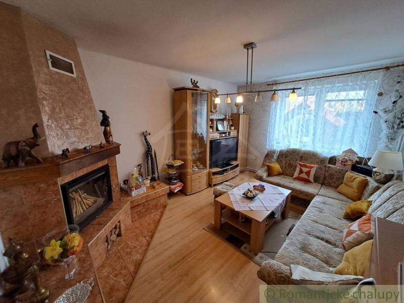 Nappali egy családi házban kandallóval, kanapéval és fa dekoros padlóval.