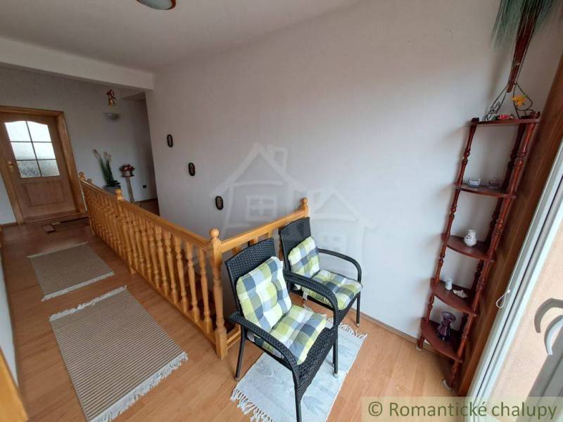 Családi ház belső tere lépcsővel, székekkel és fa dekorációjú padlóval.