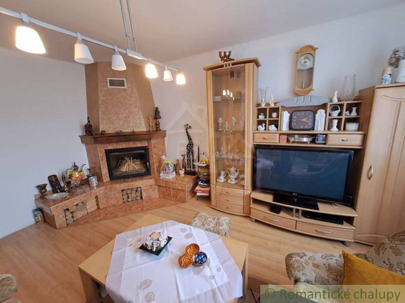 Nappali családi házban kandallóval, fa hatású padlóval és vitrinnel.