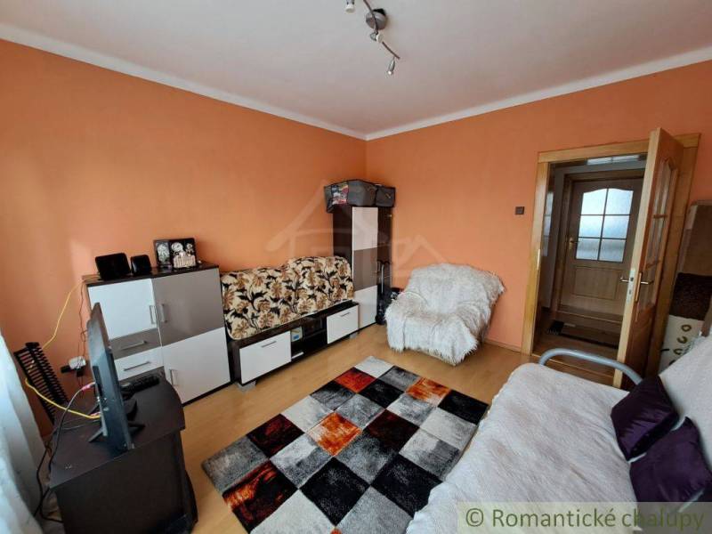 Nappali családi házban bútorokkal, televízióval és fa dekorációjú padlóval.