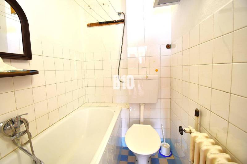 Családi ház fürdőszobája káddal, WC-vel és csempézett falakkal.