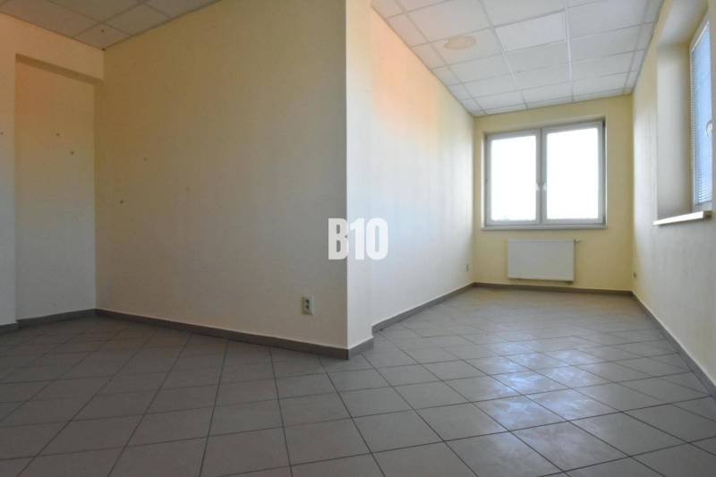 Svetes helyiség, világos falak, ablak és padlóburkolat az irodában.