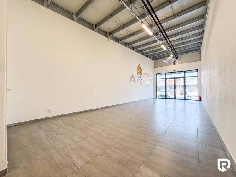 Kereskedelmi helyiségek belső tere nagy formátumú ablakokkal és világos padlóval.