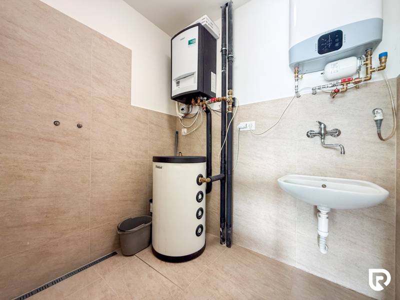 Kereskedelmi helyiségek belső tere fűtési rendszerrel, mosdóval és fa dekorációjú padlóval.