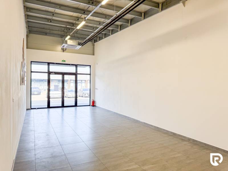 Tágas üzlethelyiségek járólappal és nagy ajtókkal.