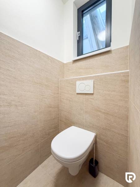 Természetes burkolatú mosdó kereskedelmi helyiségekben, egyszerű kialakítás és ablakkal.