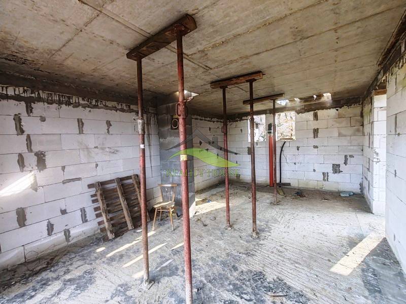 Egy kunyhó belső tere ideiglenes támaszokkal, fedetlen téglákkal és építőanyaggal.