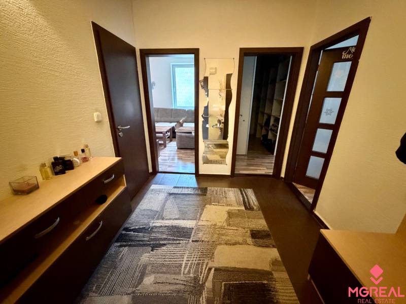 A háromszobás lakás előszobája fa dekor padlóval és szőnyeggel.