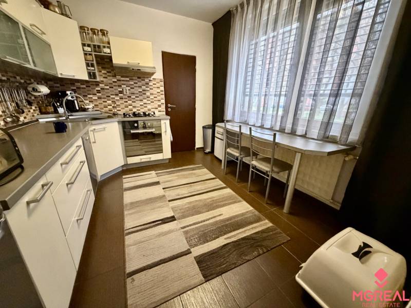 Konyha egy 3 szobás lakásban sötét padlóval és nagy ablakkal.