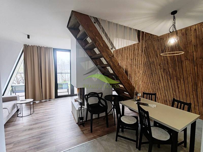 Ház fa dekor padlóval, lépcsővel és asztallal a fa lamellás fal mellett.