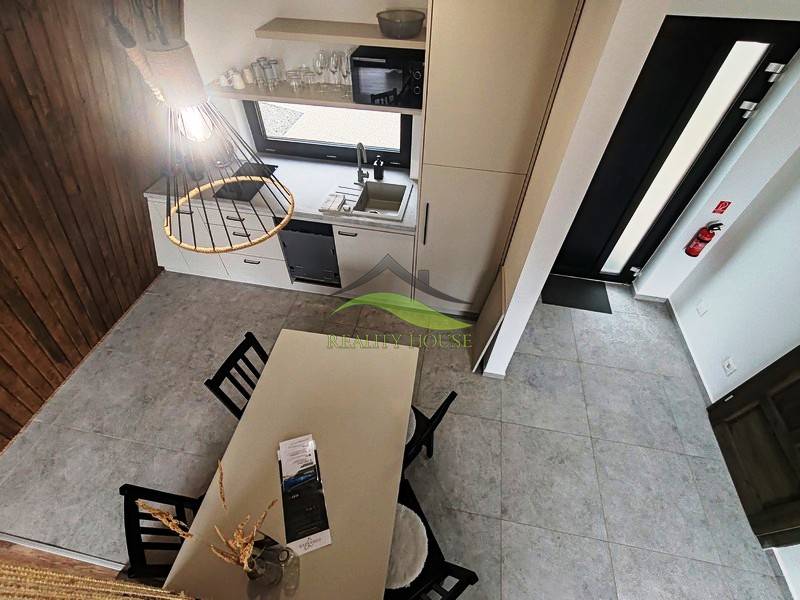 A kunyha belső tere étkezőasztallal, konyhapulttal és fa padlóburkolattal.