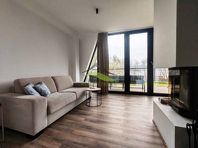 Nappali a faháznál kandallóval, kanapéval és fa dekorációjú padlóval.