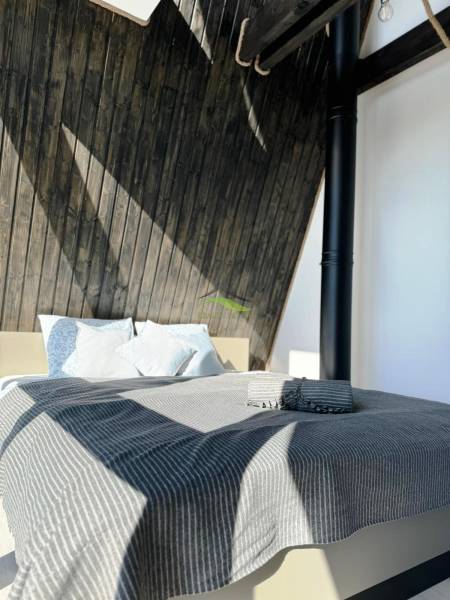 Ágy csíkos takaróval és faház falakkal.