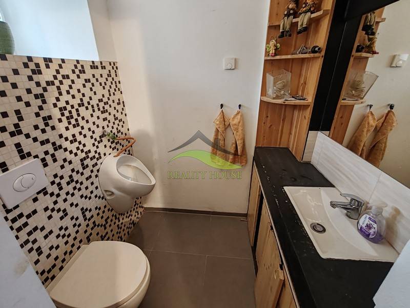 Családi ház fürdőszobája mosdóval, tükörrel és mozaik csempékkel.