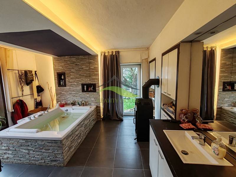 Tágas fürdőszoba káddal és csempékkel egy családi házban, fa dekorációjú padlóval.