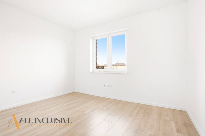 Üres szoba világos falakkal és fa dekorációjú padlóval egy háromszobás lakásban.