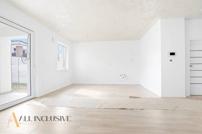 Tágas szoba fa mintázatú padlóval és nagy ablakokkal egy háromszobás lakásban.