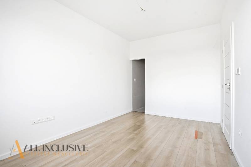 Szoba egy háromszobás lakásban fehér falakkal és fa dekorációjú padlóval.