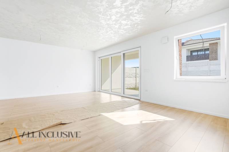 3 szobás lakás fehér falakkal és fa mintázatú padlóval.