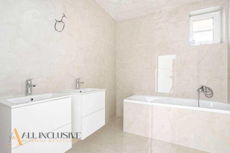 Fürdőszoba két mosdóval és káddal egy háromszobás lakásban.