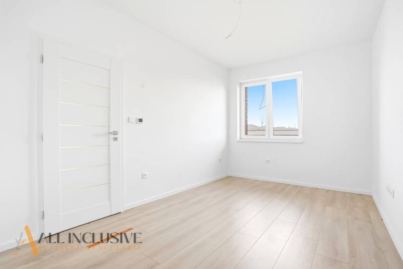 Szoba egy háromszobás lakásban fehér falakkal és fa dekorációjú padlóval.