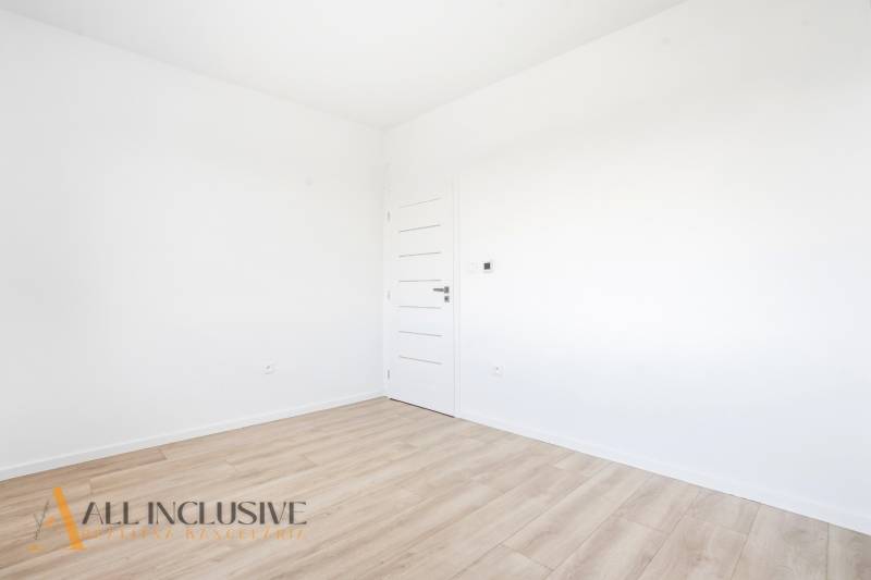 Üres szoba fehér falakkal és fa dekorációjú padlóval egy háromszobás lakásban.