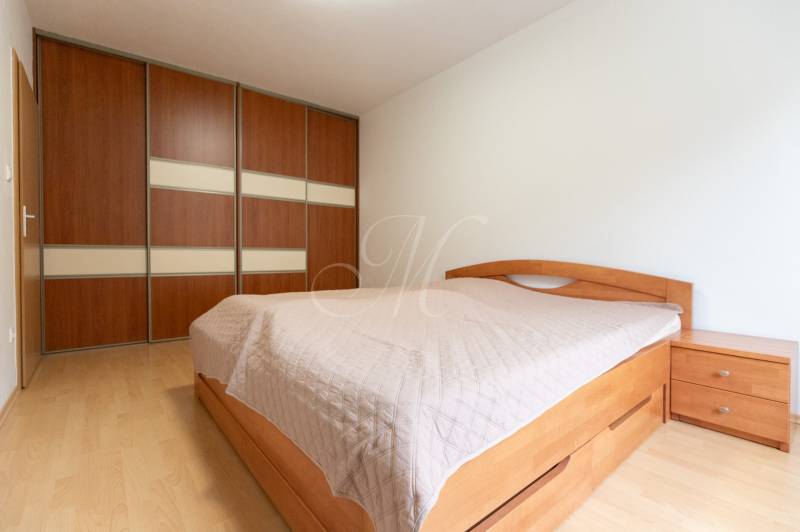 Hálószoba fa dekor padlóval és beépített szekrénnyel egy kétszobás lakásban.