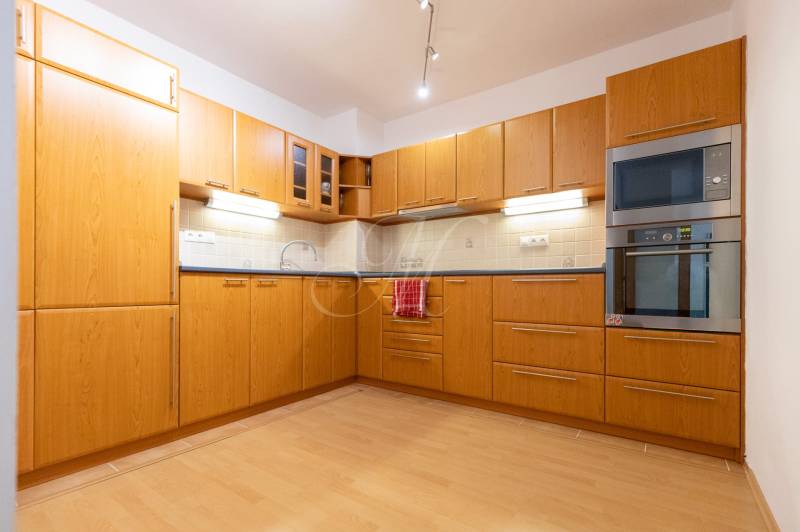 Két szobás lakás konyhája fa mintás padlóval és beépített készülékekkel.