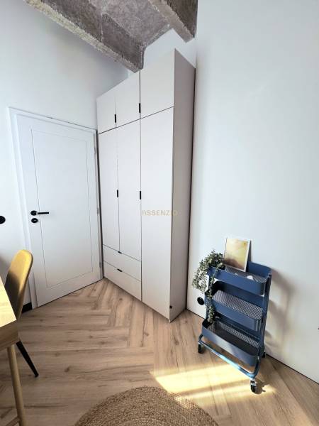 Stílusos sarok egy háromszobás lakásban, fa hatású padlóval és tároló polccal.