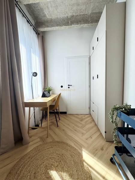 A 3 szobás lakásban a padló, az íróasztal és a magas fehér szekrény fa dekorációja dominál.