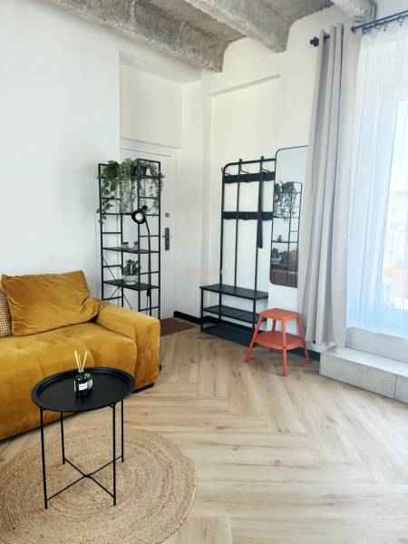 A háromszobás lakásban található egy mustársárga kanapé, egy állvány, egy tükör és fa dekorációjú padló.