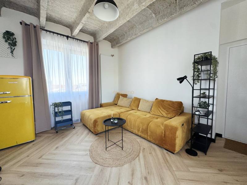 Nappali fa hatású padlóval, sárga kanapéval és retro hűtőszekrénnyel.