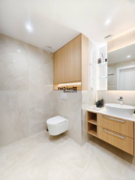 Fürdőszoba fa dekoros padlóval egy kétszobás lakásban, világos csempék és függesztett WC.