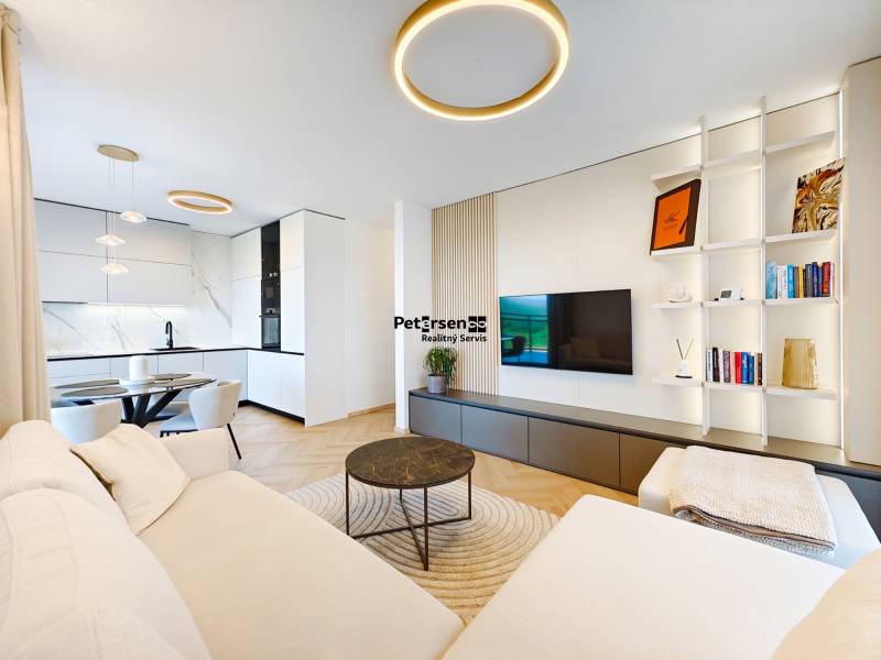 Nappali egy kétszobás lakásban kanapéval, konyhával és fa dekoros padlóval.