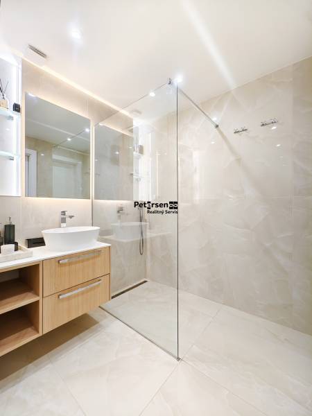 Fürdőszoba egy kétszobás lakásban nagy tükörrel és üveg zuhanykabinnal.