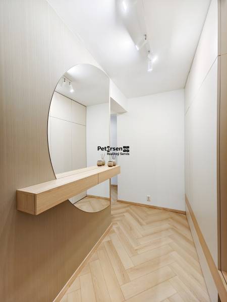 Előszoba fa mintázatú padlóval és nagy tükörrel egy kétszobás lakásban.