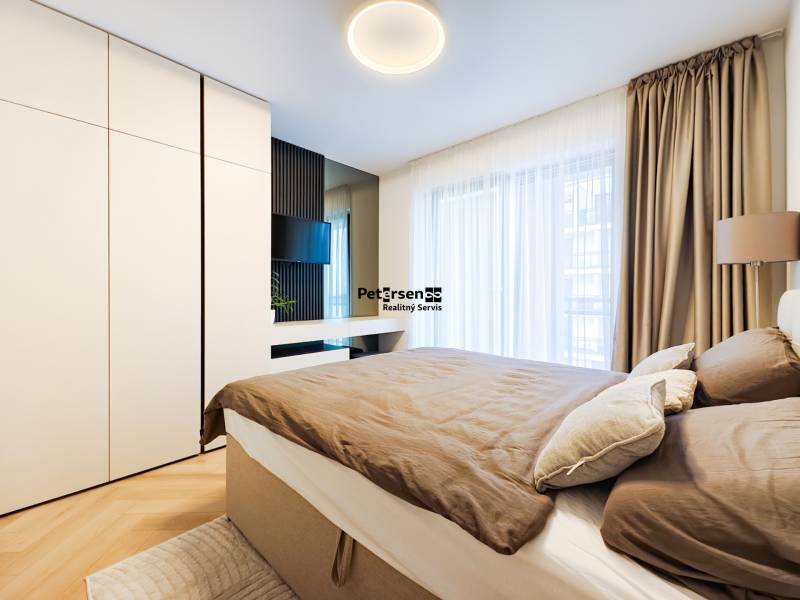 Hálószoba egy kétszobás lakásban fa hatású padlóval, nagy szekrénnyel és függönyökkel.