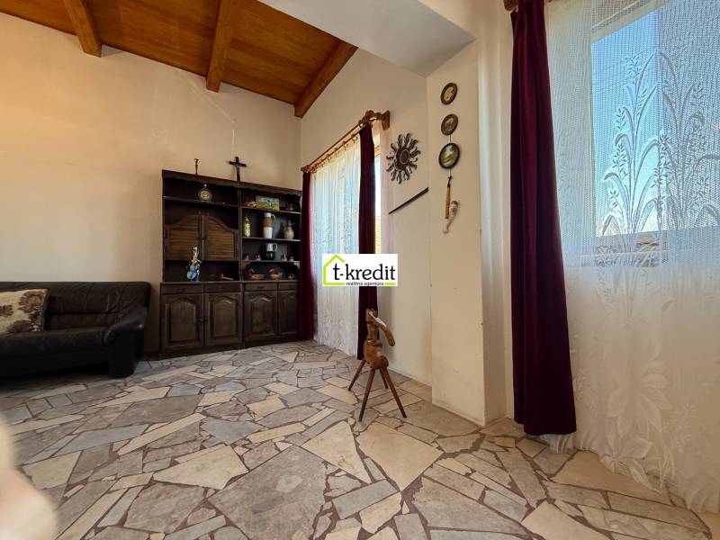 Belső tér egy kőpadlós és fagerendás mennyezetű házikóban.