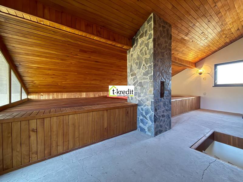 Padlásszoba fa burkolattal és kő kéménnyel a házikóban.