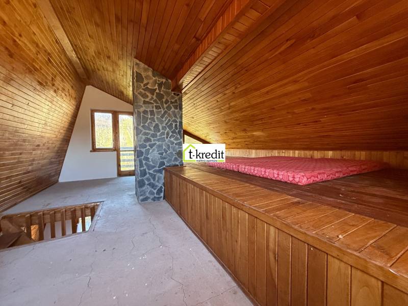 A faház padlása fa dekorációval és kő kéménnyel emlékeztet egy hangulatos pihenőhelyre.