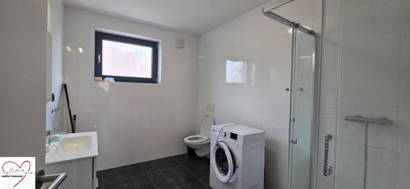 Fürdőszoba zuhanyzóval, mosdóval és mosógéppel egy háromszobás lakásban.